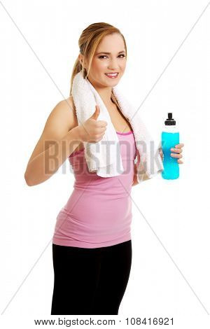 Attractive woman in fitness clothes with isotonic drink and ok sign.