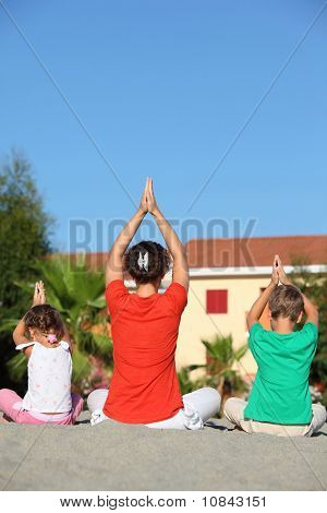 Frau mit Kindern sitzen Zuges zurück auf Sand In Pose des Yoga und zur Festlegung der Hände Lift Hände nach oben