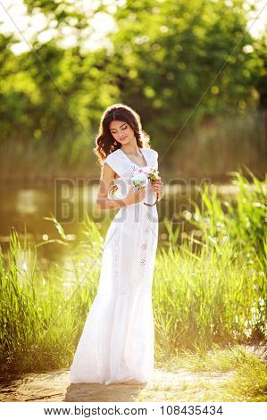 Beautiful young girl in a light sundress in spring garden