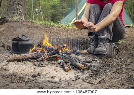 Girl Sitting While Camping Near The Fire Heated And Drink Hot Tea