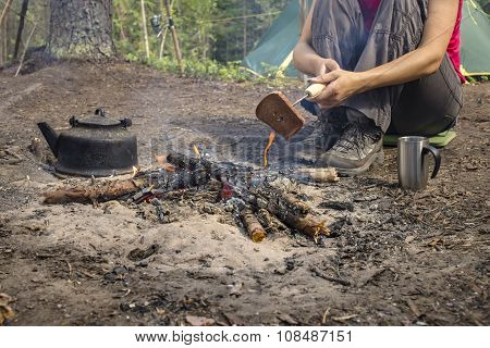 Girl Sitting While Camping Near The Fire Heated And Drink Hot Tea