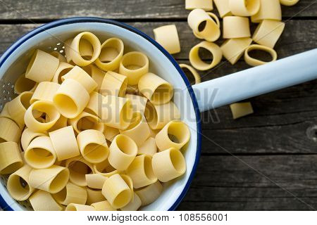 uncooked pasta calamarata in colander