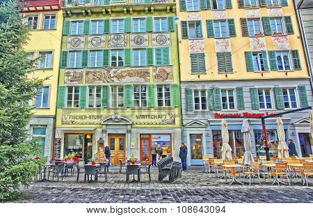 LUCERNE SWITZERLAND - JANUARY 04 2015: Outdoor street cafe tables ready for service on the right bank of the River Reuss at a picturesque square Muhlenplatz in Lucerne Switzerland.
