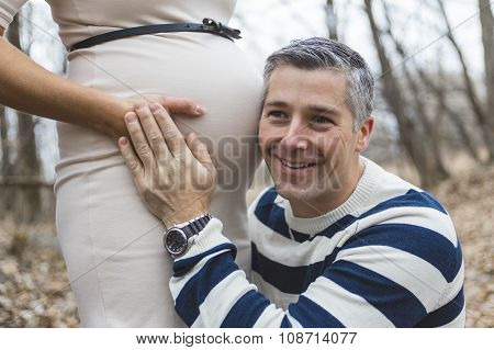 Beautiful outdoor pregnant couple portrait in autumn nature