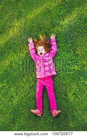 Redhead Girl Lying On The Green Grass In Park.