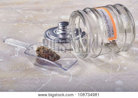 Marijuana bud on scooper with glass jar over white background