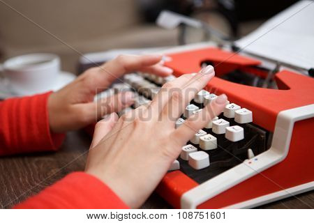 human hands writing on red typewriter
