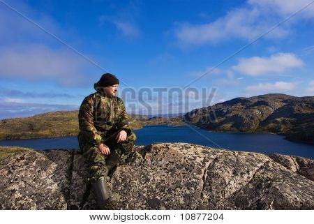 Mann sitzt auf einem Berg. Grat Musta Tunturi.
