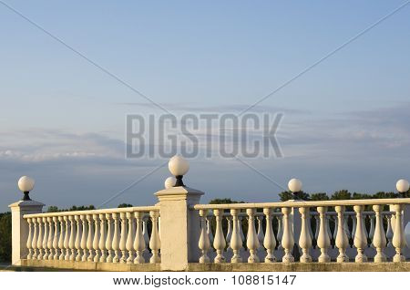 Decorative Fence Of Columns On Promenade On Background Of Blue Sky And Clouds