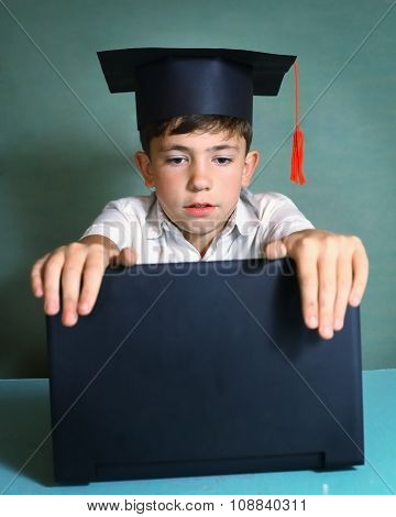 boy in graduation cap with  notebook