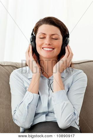 Sonriente mujer escuchando música con Headphones en la sala de estar