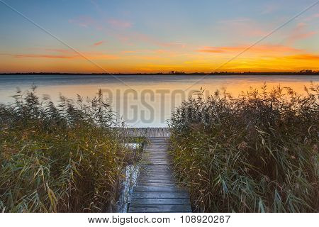 Orange Sunset Over Jetty On The Shore Of A Lake