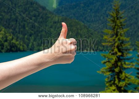 Thumb on the background of a mountain lake