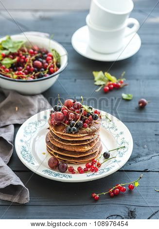 Breakfast set. Buckwheat pancakes with fresh berries and honey on rustic plate over black wooden tab