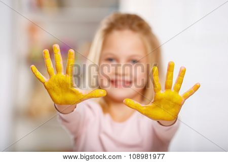 Kid hands covered in yellow paint.
