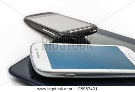 White Smartphone On Tablet & Black Mobile Leaning On Tablet