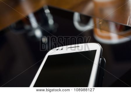 Smartphone And Tablet Besides Coffee & Coffeemaker On A Table