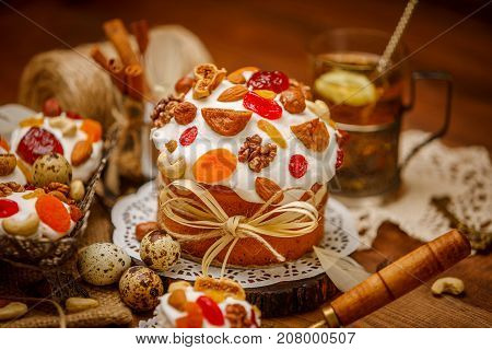 Traditional Easter cake with decorations and cupcakes on wooden table