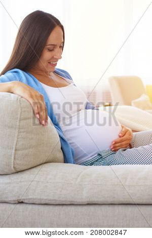 Side view of delicate mother keeping hands on belly. Concept of maternity 