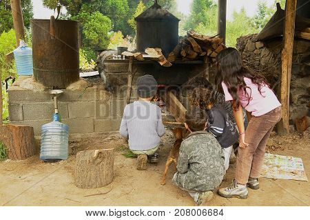 LES PALMISTES, FRANCE - DECEMBER 12, 2010: Unidentified kids burn traditional outdoor oven to produce geranium oil - a fragrant oil used in cosmetics and culinary dishes - at Les Palmistes, Reunion island, France.