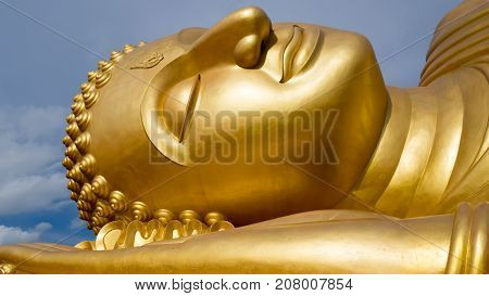 Reclining Golden Buddha face at wat Lampho Khoyo Songkhla Thailand. Gold Buddha statue.