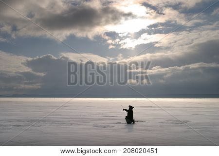 Fisherman On The River Covered With Ice