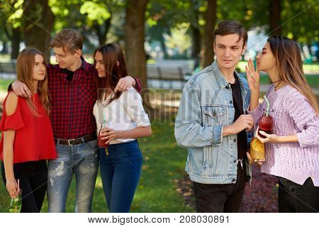 Jealousy and envy in friends relationship. Cheerful young people with detox cocktail having outdoor summer party