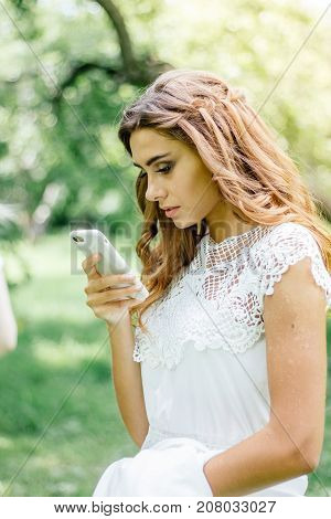 Beautiful young bride chating by mobile phone during wedding.