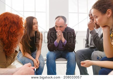 Meeting of support group. Depressed man sitting at rehab group therapy. Psychotherapy, depression, life issues concept