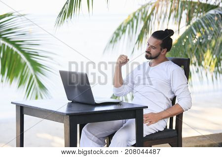 telecommuting, businessman relaxing on the beach with laptop and palm, freelancer workplace, dream job. Showing win