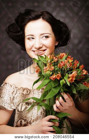 Portrait of beautiful happy woman with flowers in hands. Young attractive young girl holds the bouquet of red and yellow flowers.