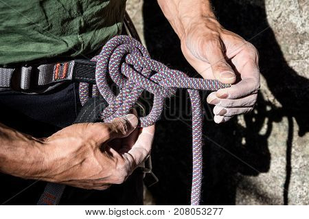 mountain climber tying rope in double bowline knot