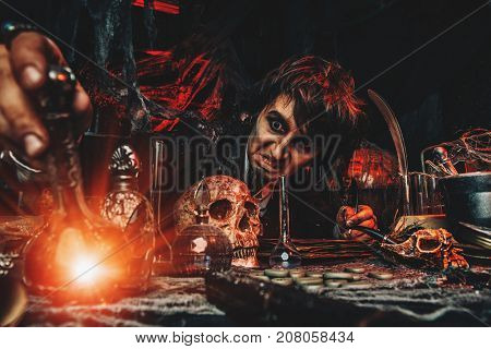 Medieval scientist creates a magical elixir in his laboratory. Alchemist. Halloween.