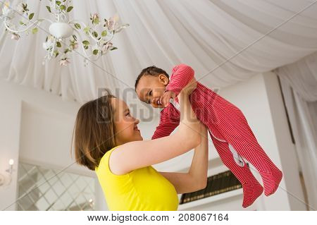 happy family. Mother throws up baby, playing at home.