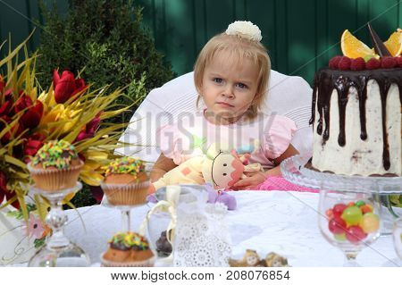 Girl birthday. A little white-haired girl of two years is trying a birthday cake. Little girl celebrating second birthday.
