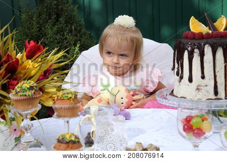 Girl birthday. A little white-haired girl of two years is trying a birthday cake. Little girl celebrating second birthday.