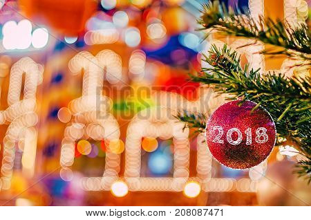 Bright Christmas and New Year background. Christmas and New Year decorations background. Red christmas ball on fir branch with text 2018.