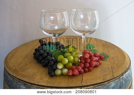 Glass and red white rose grapes and on old oak barrel