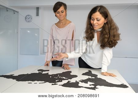 Twins girls fixing the world map on the table