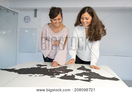 Twins girls fixing the world map on the table