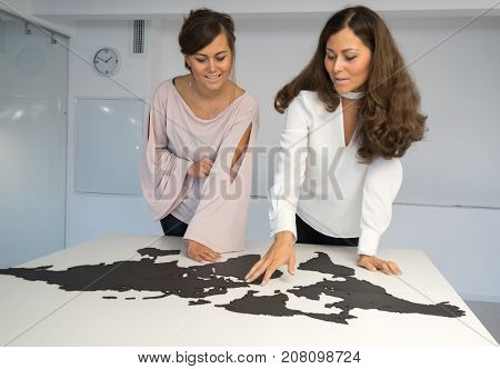 Twins girls fixing the world map on the table