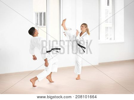 Young man and woman practicing karate in dojo