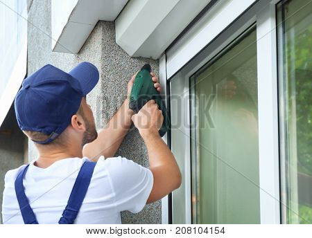 Man installing roller shutter on window