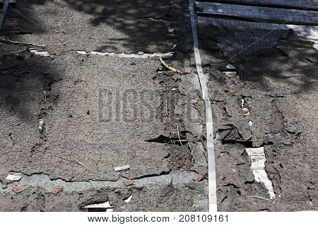 The Old Destroyed Roof, Covered With A Cracked Ruberoid. Photo Close-up In Sunny Weather