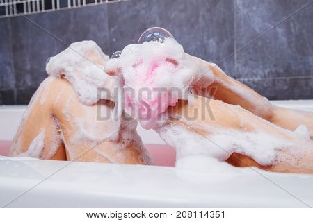 Close Up Of Woman Washing Arm With Sponge In Bathtub In The Bathroom