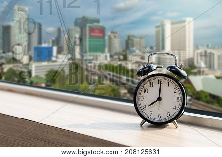 Vintage alarm clock at windows with abstract Blurred photo of sky train with traffic jam on early morning traffic tranportation concept