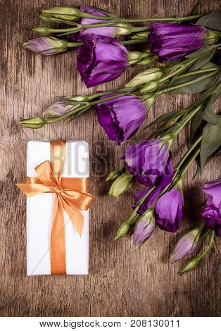 Gift box with a golden bow and flowers eustoma.