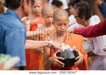 LAMPANG THAILAND - JULY 9 2017: Unidentified people offer food to monks in Devo tradition on JULY 9 2017 in Lampang Thailand. Tak Bat Devo is the tradition in end of Buddhist Lent.