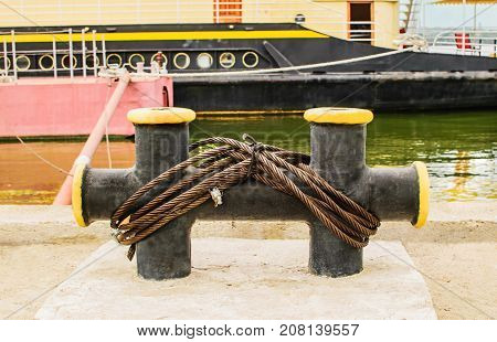 Mooring rope tied to the bollard at the pier. Nautical mooring rope. Boat moored by the river