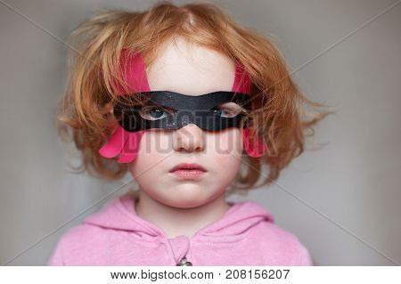 Red-haired girl wearing a mask for the carnival